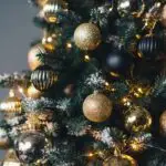 Festlich geschmückter Weihnachtsbaum mit goldenen und schwarzen Christbaumkugeln und Lichterkette.
