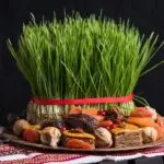 Grünes Weizengras (Sabzeh) mit rotem Band, dekoriert mit Trockenfrüchten und Nüssen.