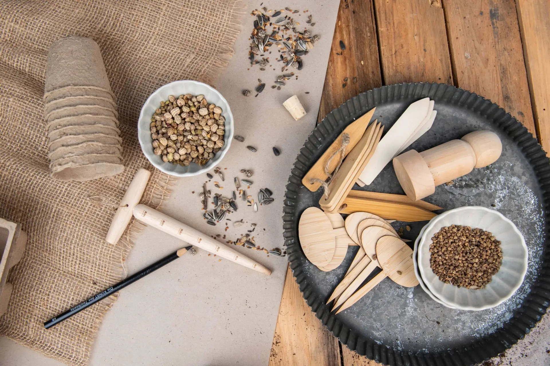 Holz Pflanzschilder, Saatgut und Anzuchtzubehör auf einem Tisch arrangiert.