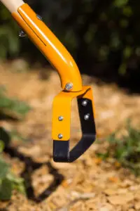 Detail einer Pentelhacke mit gelbem Metallbügel und schwarzer Stahlklinge.